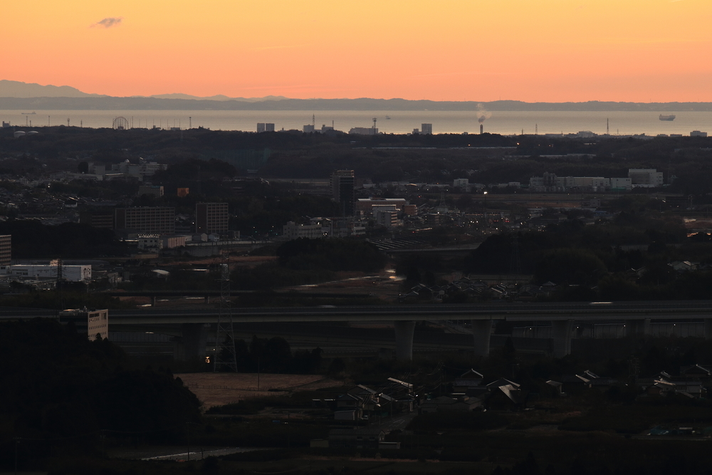 公園の展望台から見る夜明け前の風景には住宅街や市街地や小高い山の写った画像